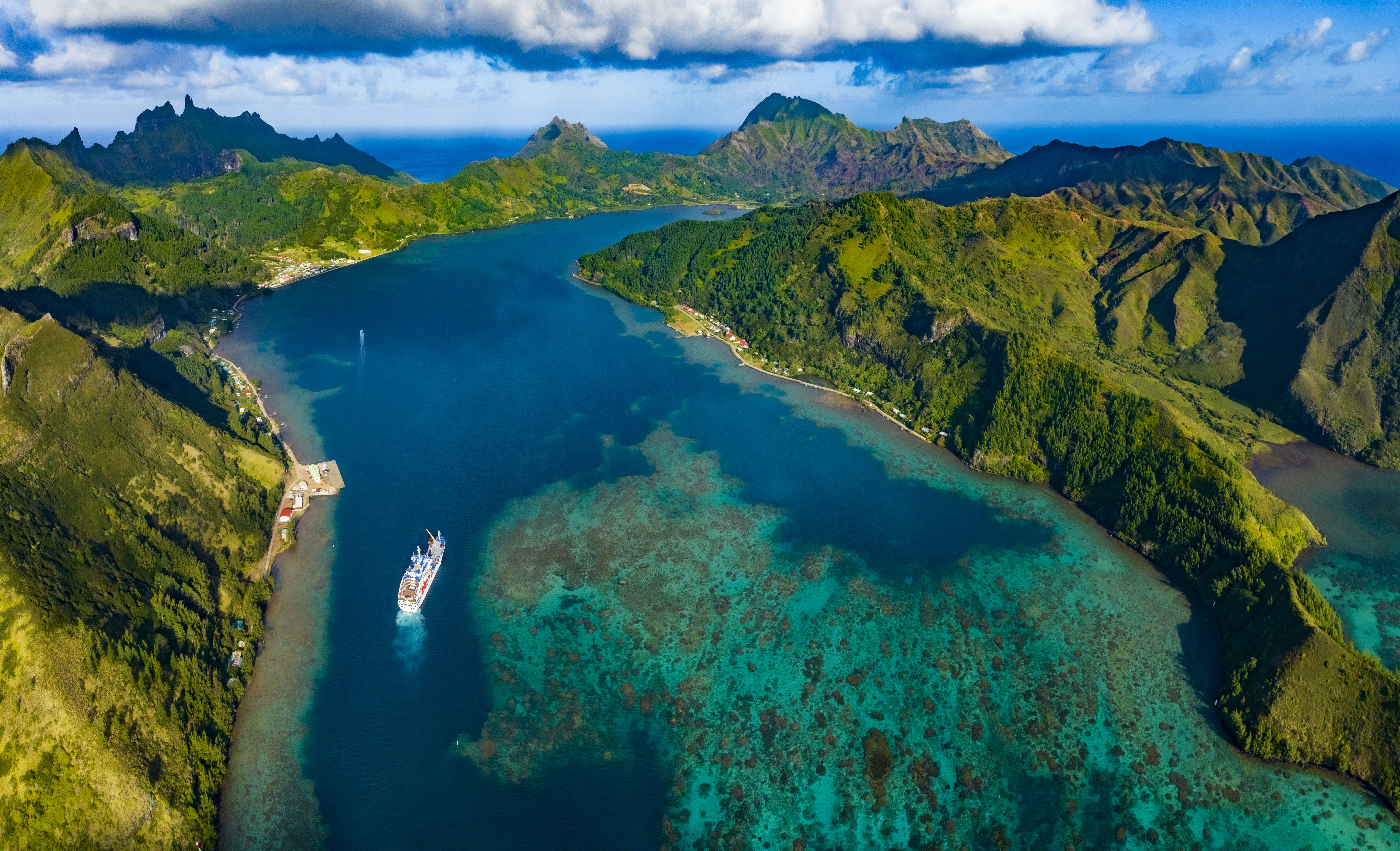 Passengers enjoying the sun deck and swimming pool on an Aranui cruise ship with scenic island views in the background.