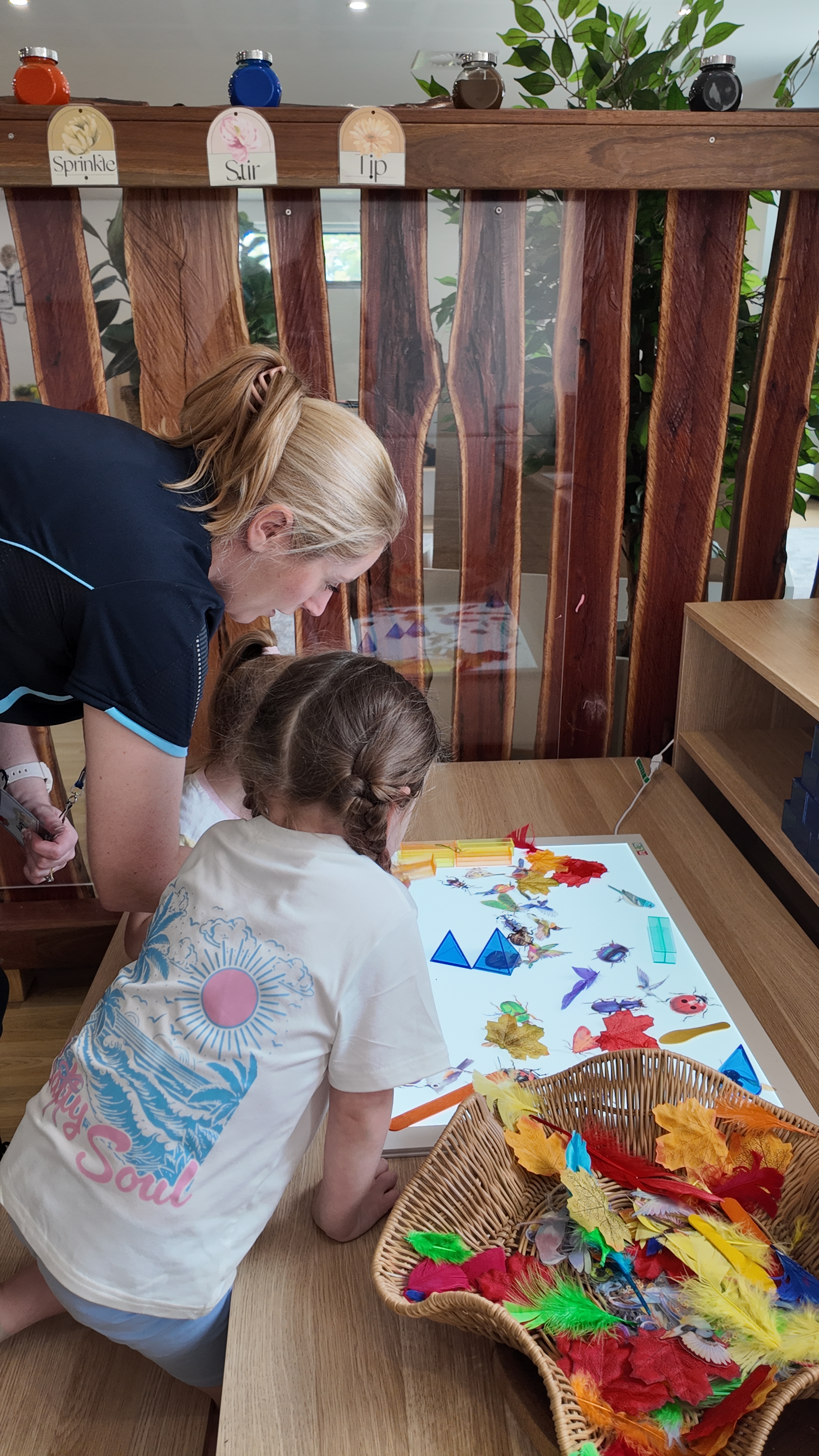 Educator smiling and interacting joyfully with young children in a bright classroom setting