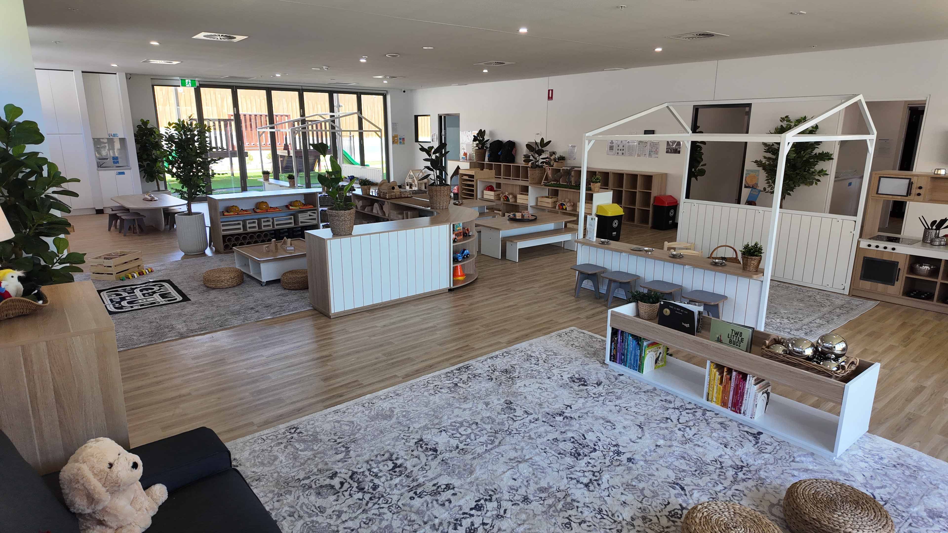 Children playing with premium educational wooden resources in a well-lit, modern childcare room